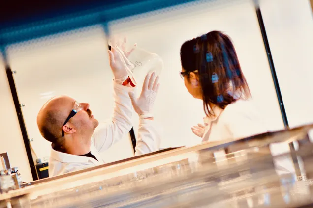 Photo of a man and a women in a laboratory setting from a far.